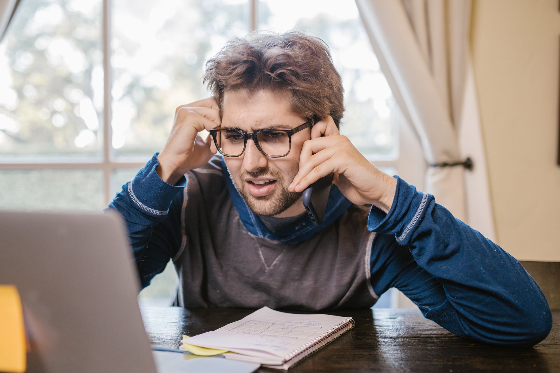 A man looking confused and frustrated while reviewing renovation numbers on his laptop